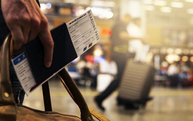 Un pasajero sujeta sus billetes antes de coger el avión.