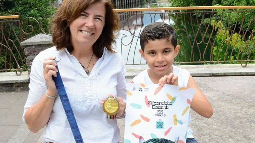 Los encargados del chupinazo, Teresa Motos Izeta y Sami Ouady Dyian, con el stick, la medalla de oro y el cartel de fiestas de Elizondo.