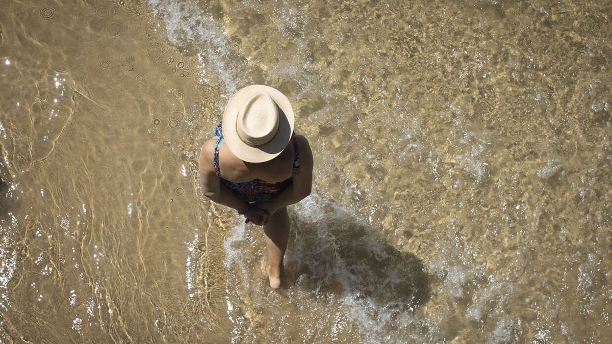 Una mujer disfruta de un paseo en la orilla de la playa de La Concha de Donostia