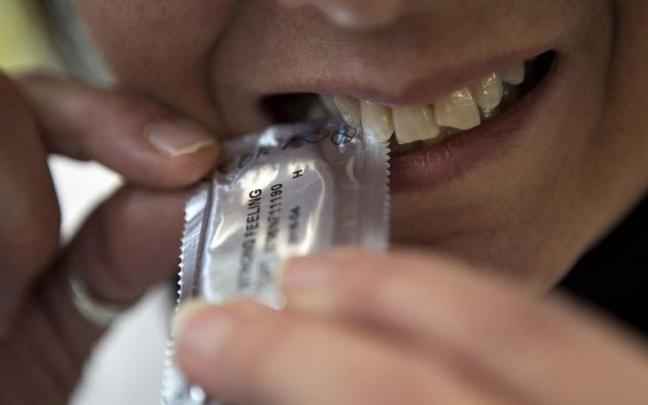 Una persona rompe el precinto de un preservativo Una persona rompe el precinto de un preservativo