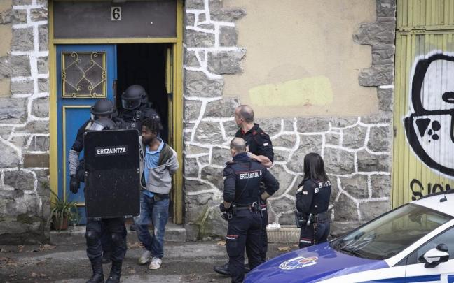 Agentes del equipo de intervención rápida de la Ertzaintza conducen al hombre que se había atrincherado en una casa ocupada del Infierno