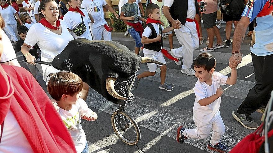 Un niño mira de frente a las astas mientras corre sin parar en el encierro de la Federación de Peñas.