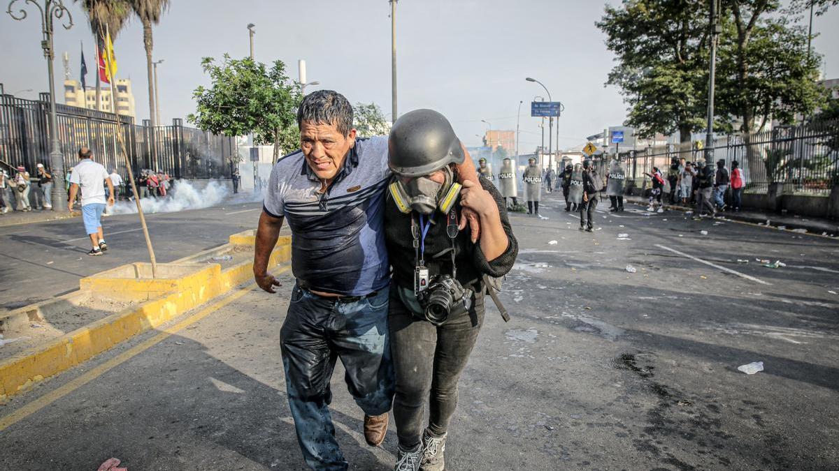 Una fotoperiodista ayuda a un hombre herido en las protestas en Lima.