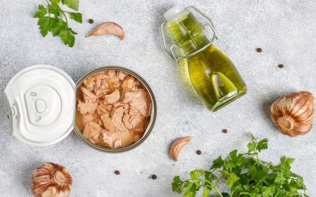 Una lata de atún en una composición con aceite, ajos y perejil. Una lata de atún en una composición con aceite, ajos y perejil.