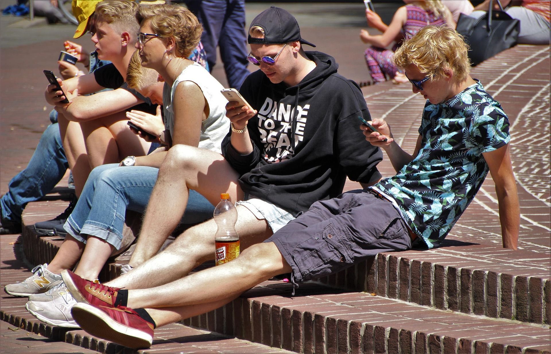 Turistas usan su teléfono sentados en la calle.