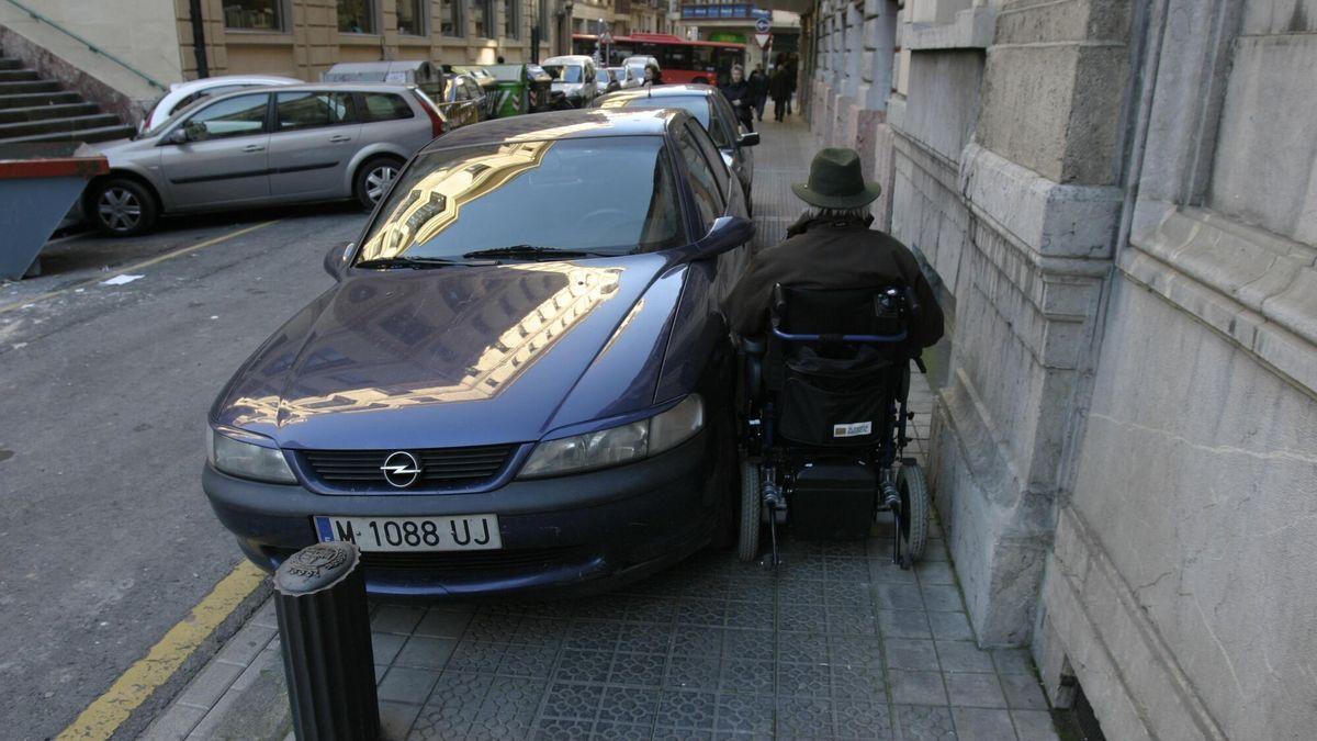 Coche aparcado en una acera donde no deja paso a un minusvalido en silla de ruedas