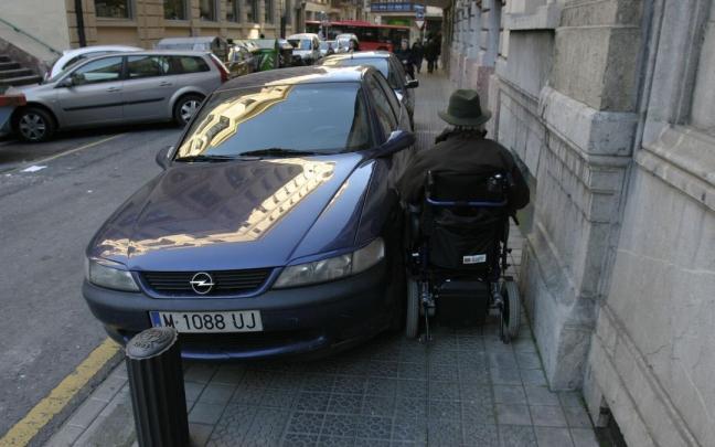 Coche aparcado en una acera donde no deja paso a un minusvalido en silla de ruedas Coche aparcado en una acera donde no deja paso a un minusvalido en silla de ruedas