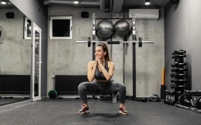 Una mujer hace una sentadilla en el gimnasio. Una mujer hace una sentadilla en el gimnasio.