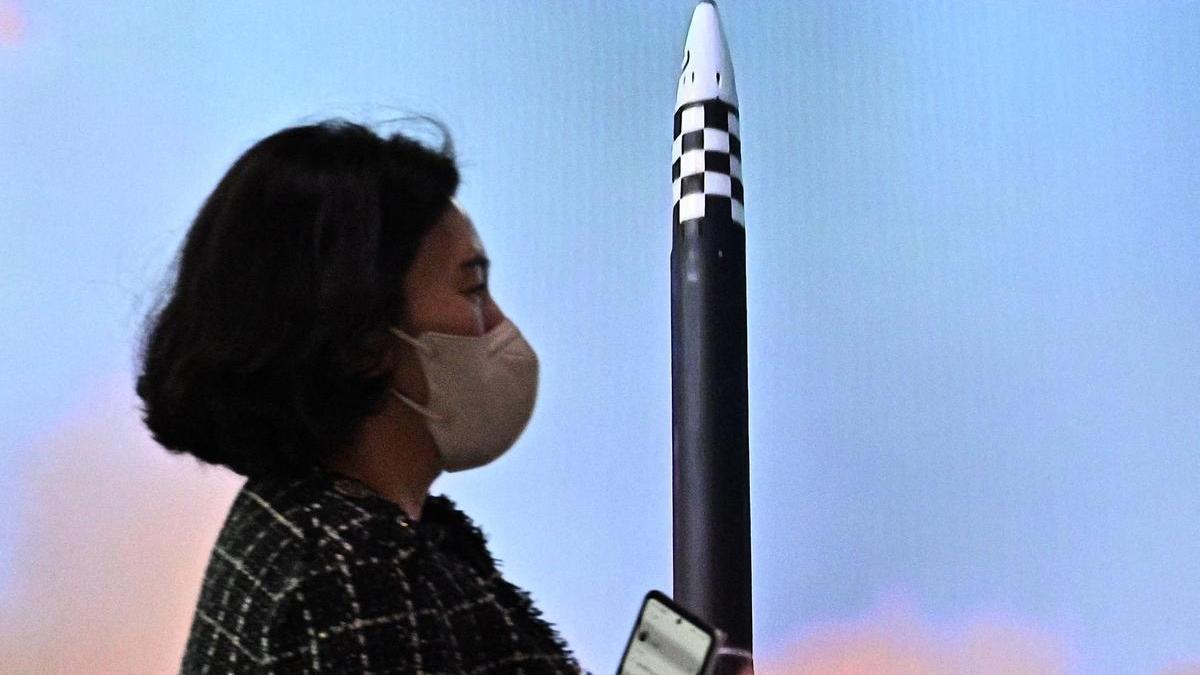 Una mujer pasa por delante de una pantalla que informa sobre el lanzamiento de un cohete norcoreano.