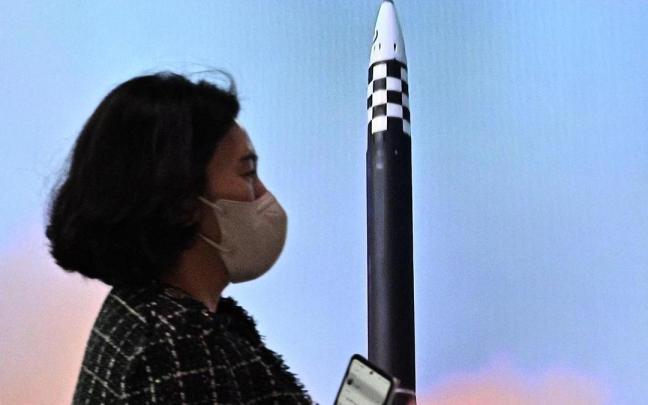 Una mujer pasa por delante de una pantalla que informa sobre el lanzamiento de un cohete norcoreano.