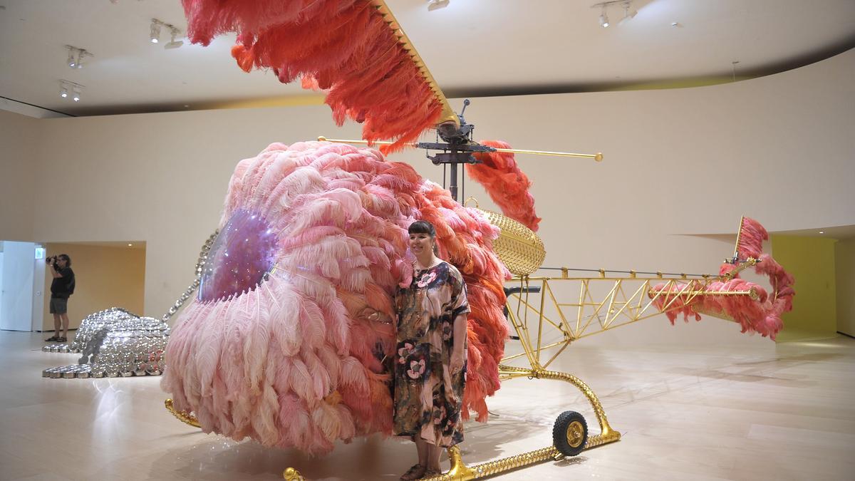 La artista posa junto a la obra ‘Lilicoptère’ , un gran helicóptero dorado, decorada con miles de abalorios brillantes de Swarovski y cubierto por una extravagante y colorida capa de plumas de avestruz.