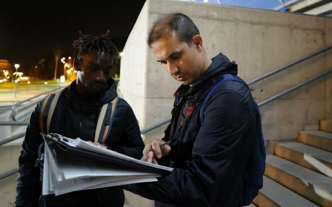 El voluntario Younes Essayoufi, marroqui de 42 años, charla con un joven de Chad mientras rellena el formulario.