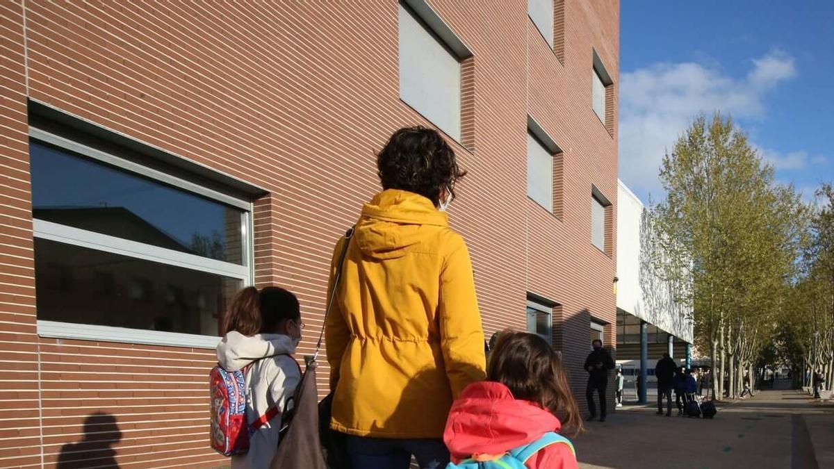 Una madre camina con sus hijas hacia la escuela.