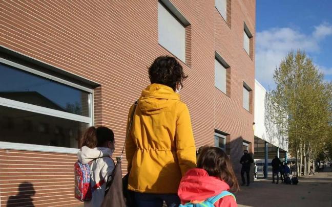 Una madre camina con sus hijas hacia la escuela.
