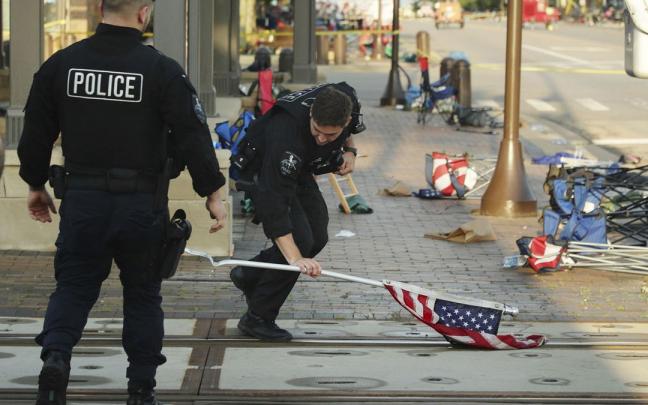 Un polic&iacute;a recoge una bandera de EEUU en la escena donde Robert Crimo dispar&oacute; durante el desfile del 4 de julio en Highland Park.