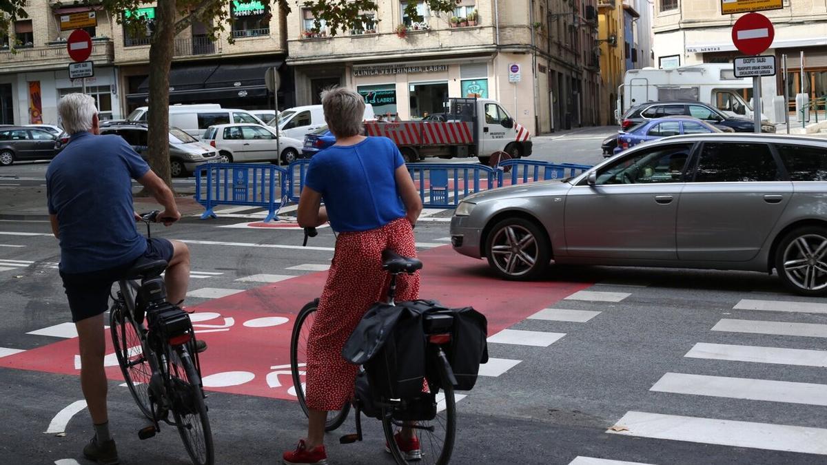 Dos ciclistas cambiando de acera junto al frontón, donde se ha colocado un semáforo y un radar.