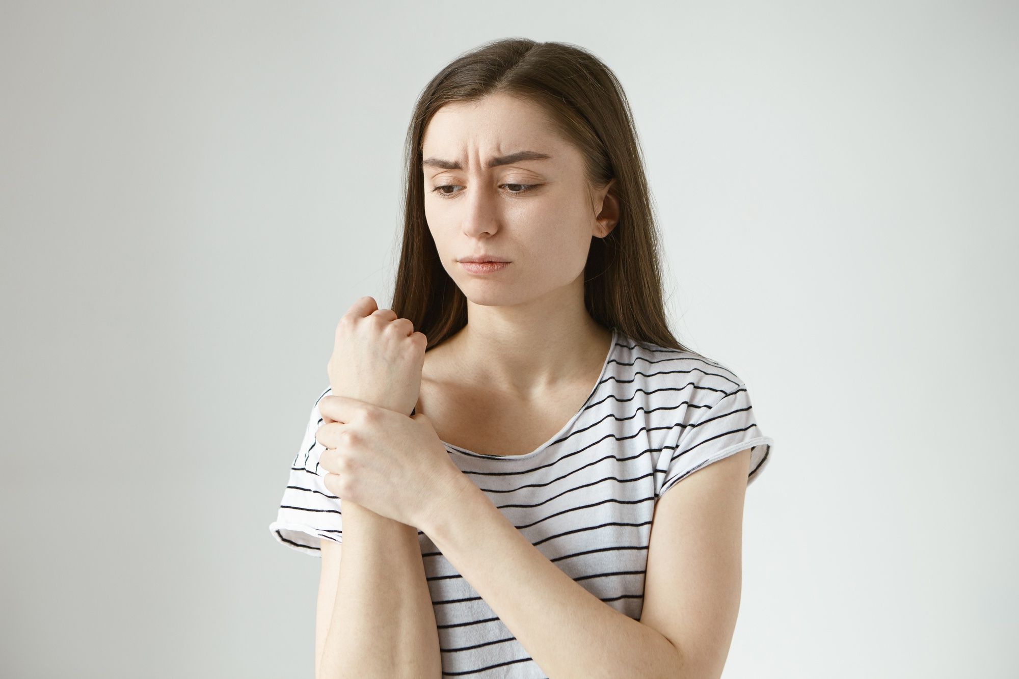 Una chica con cara de dolor se queja de la muñeca.