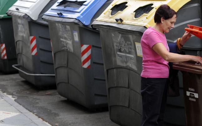 Una mujer, ajena a la información, utiliza el contenedor de residuos orgánicos Una mujer, ajena a la información, utiliza el contenedor de residuos orgánicos