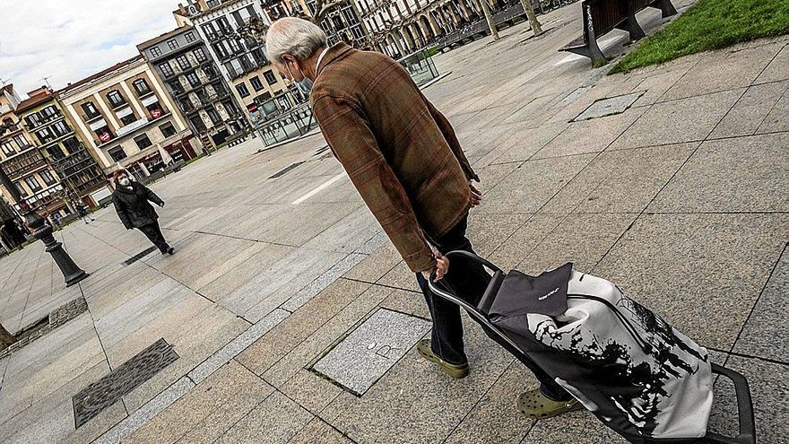 Un hombre camina con un carro de la compra por la Plaza del Castillo.