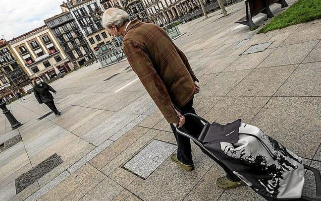 Un hombre camina con un carro de la compra por la Plaza del Castillo.