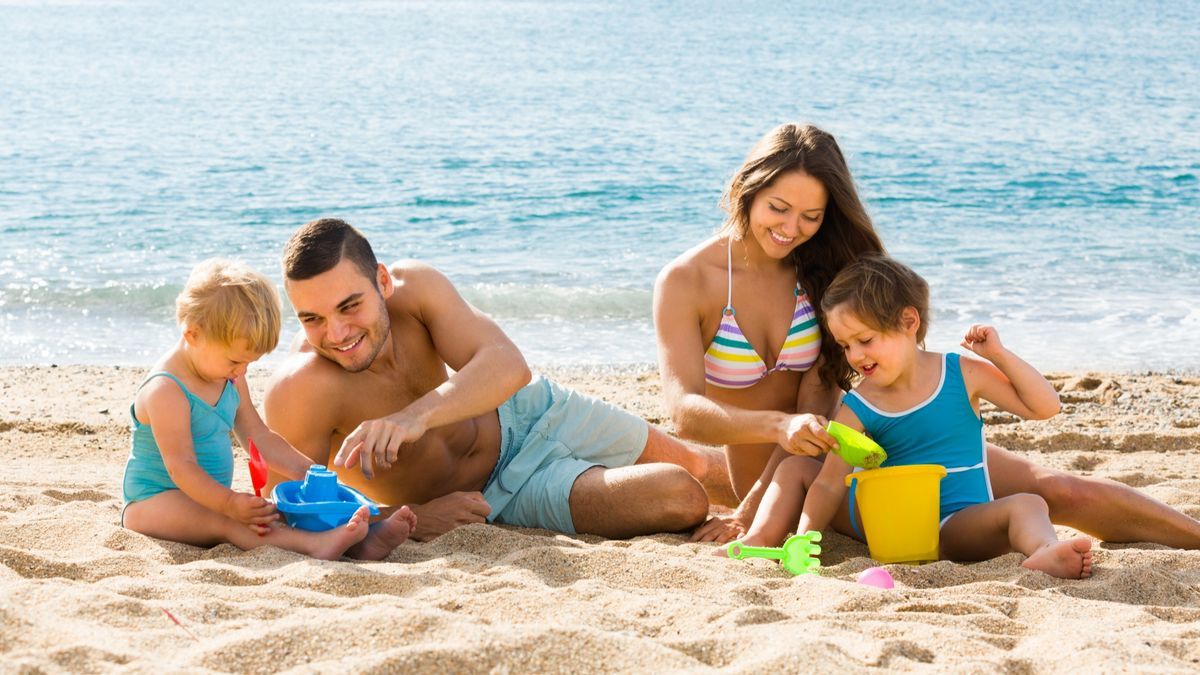 Una pareja juega con sus hijos en la arena.