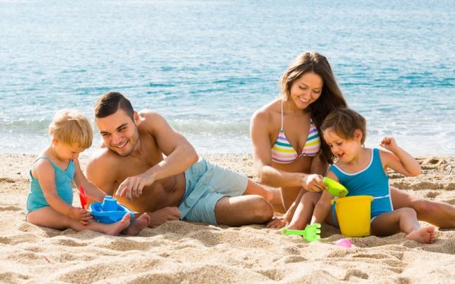 Una pareja juega con sus hijos en la arena. Una pareja juega con sus hijos en la arena.