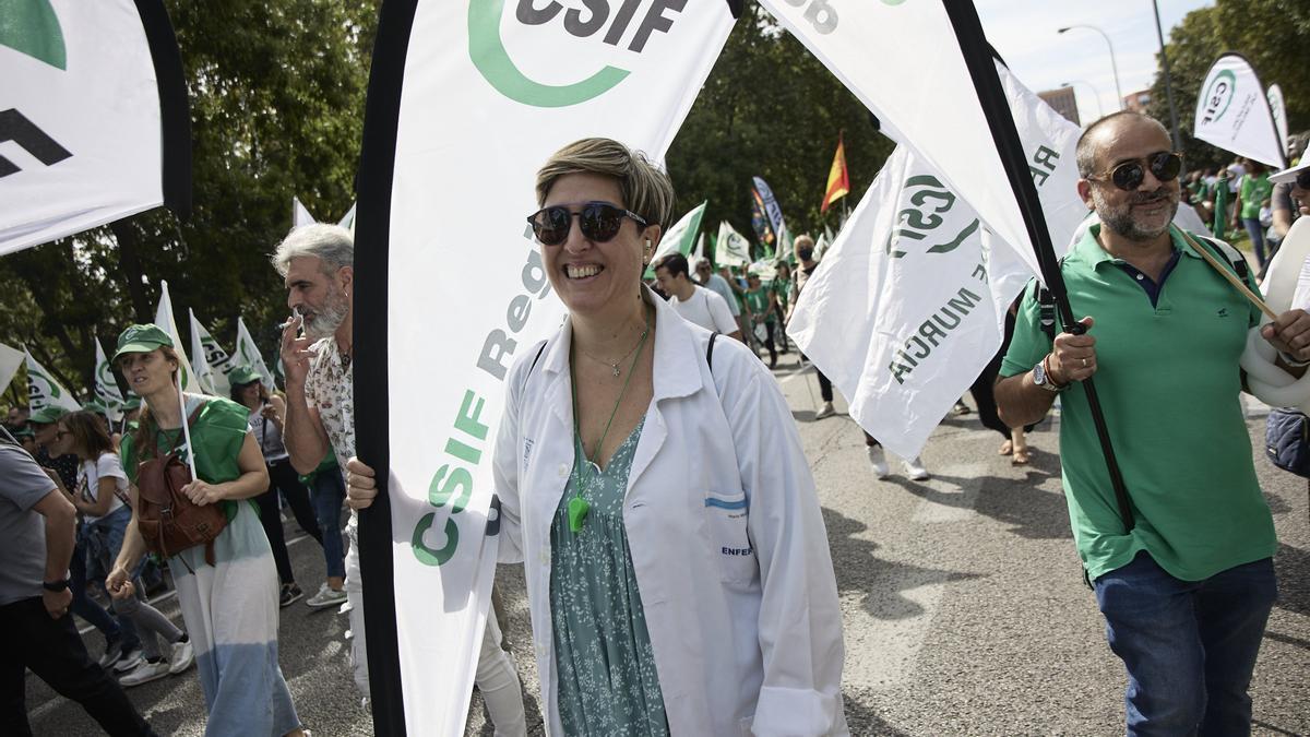 Varias personas participan, con pancartas y batas blancas, en una manifestación a favor de la subida salarial y los servicios públicos.