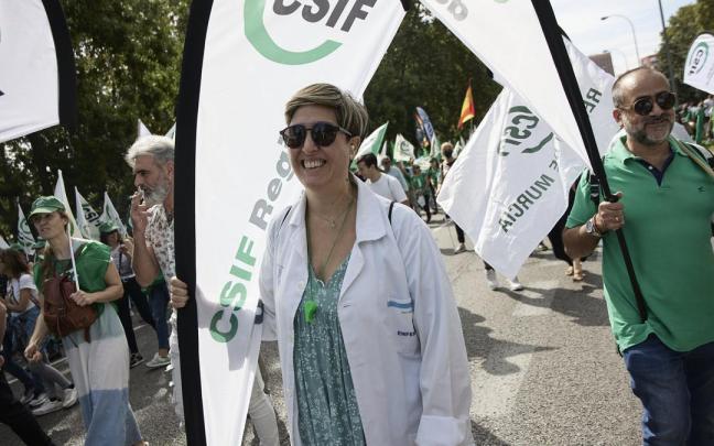 Varias personas participan, con pancartas y batas blancas, en una manifestación a favor de la subida salarial y los servicios públicos.