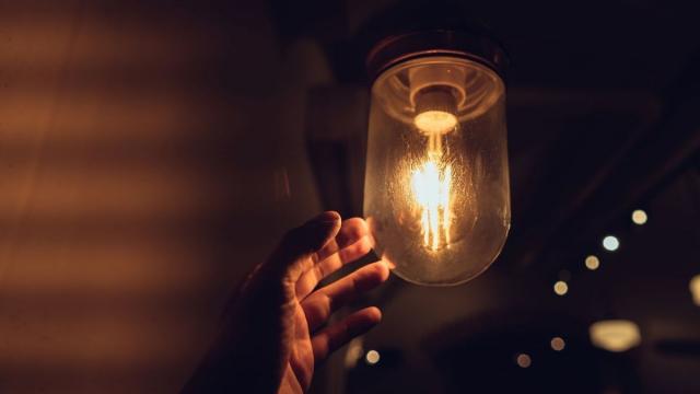 Una mano trata de sustituir una vieja bombilla.