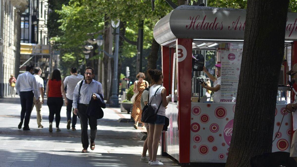 Algunas personas paseando por una calle de Bilbao en un día soleado.