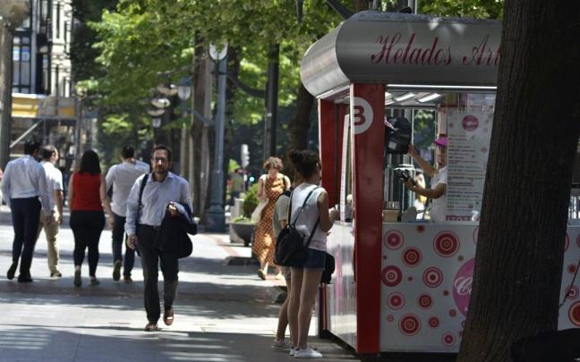 Algunas personas paseando por una calle de Bilbao en un d&iacute;a soleado.