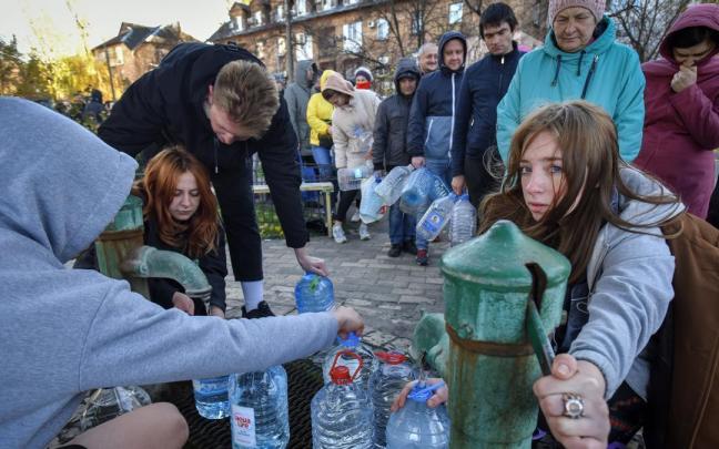 Un grupo de ciudadanos hacen cola en Kiev para llenar garrafas de agua.