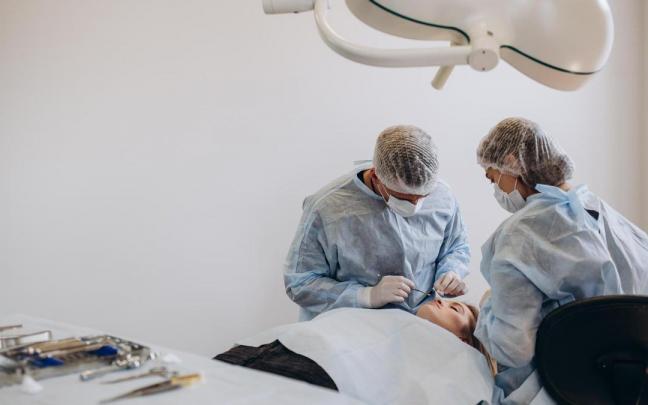 Un cirujano y su asistente realizan una operación de estética.