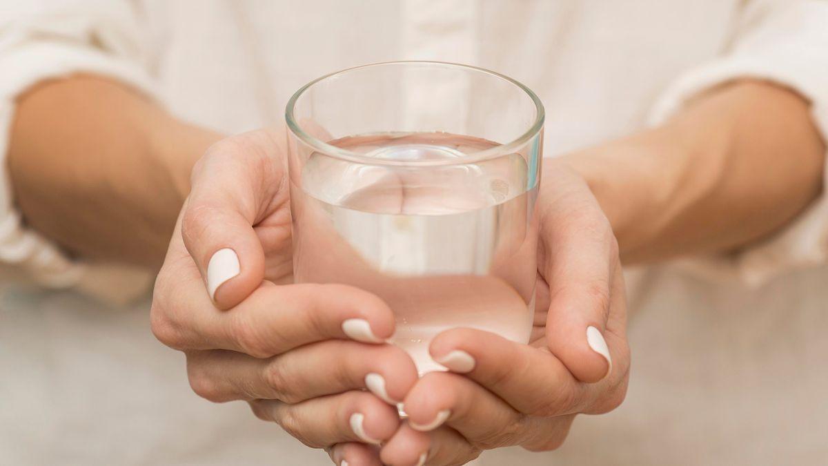 Manos de mujer sujetando un vaso de agua.