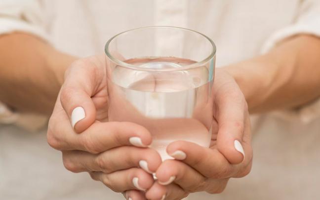 Manos de mujer sujetando un vaso de agua. Manos de mujer sujetando un vaso de agua.