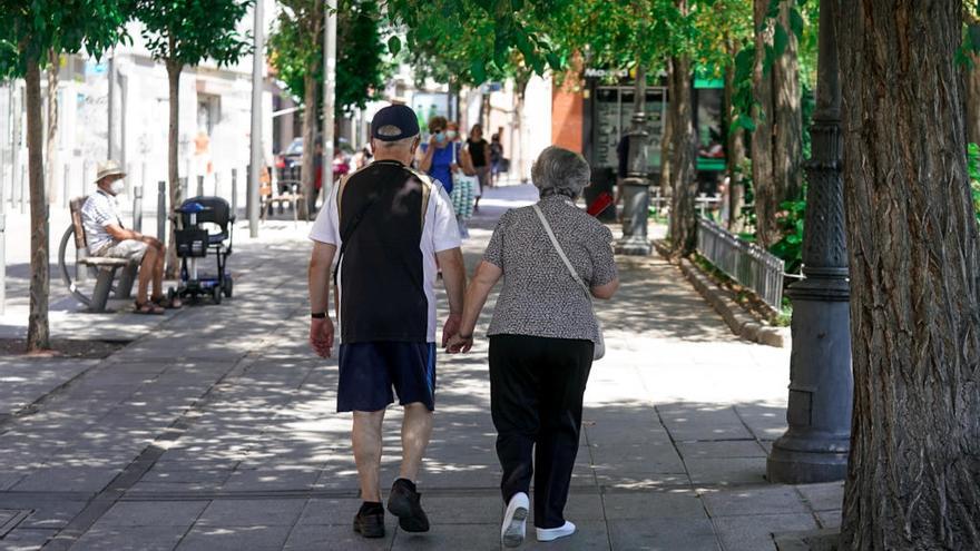 Una pareja de ancianos camina por la calle cogida de la mano.