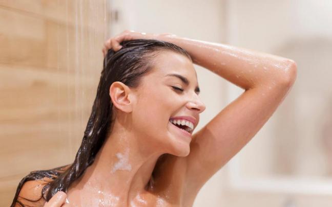 Una mujer aclara su pelo bajo la ducha.