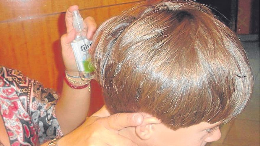 Una m adre echa un spray antipiojos a su hijo. | FOTO: E.P.