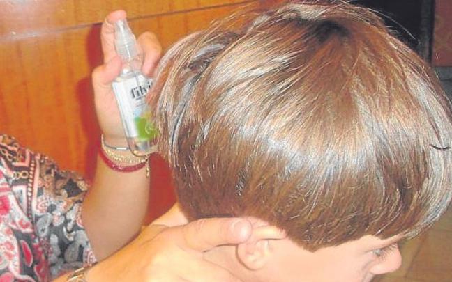 Una m adre echa un spray antipiojos a su hijo. | FOTO: E.P. Una m adre echa un spray antipiojos a su hijo. | FOTO: E.P.