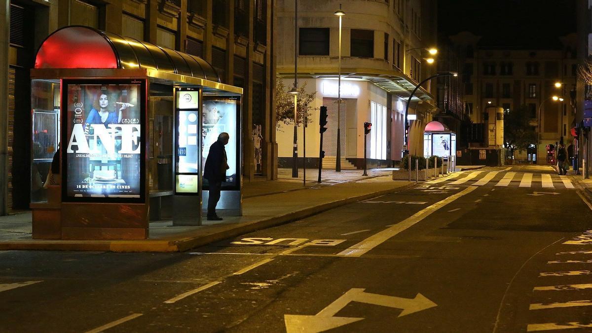 Un hombre espera la llegada de la última villavesa en Pamplona.