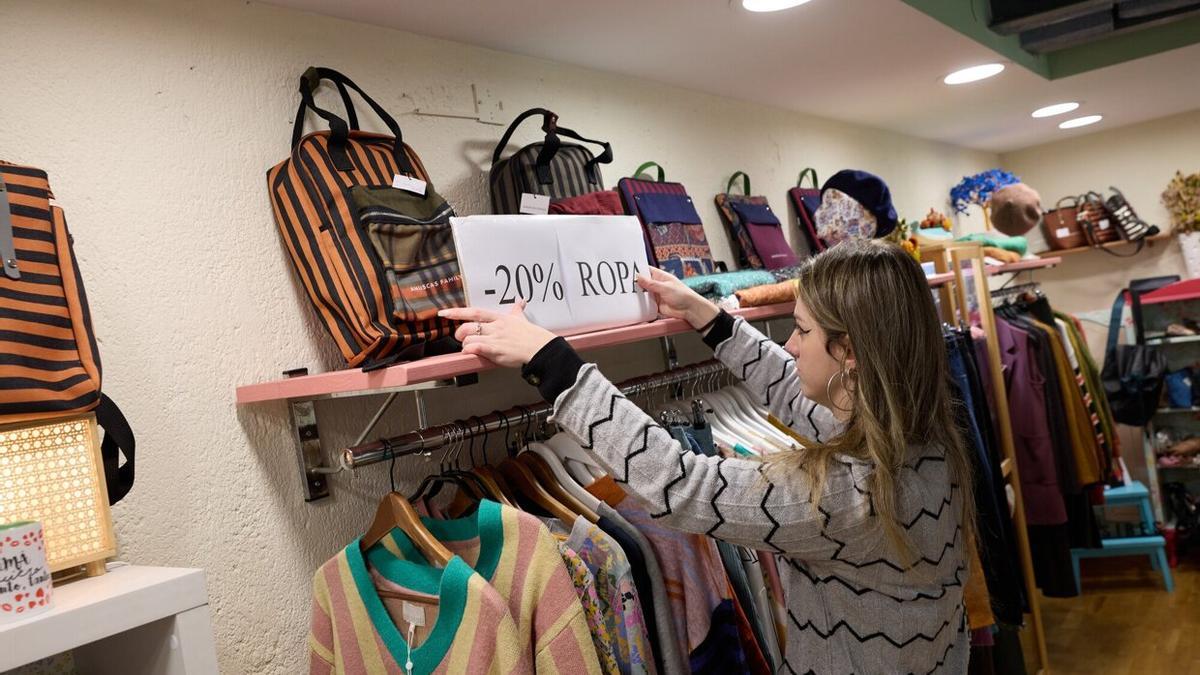 Amaia Armendáriz, dependienta de la tienda Ruhna, coloca un cartel de descuento.