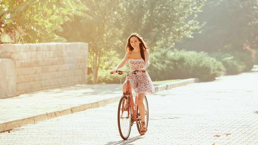 Una chica joven disfruta de un paseo en bicicleta con un vestido puesto.