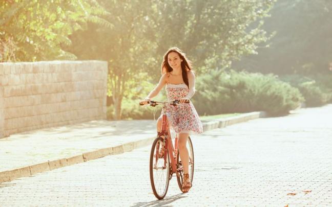 Una chica joven disfruta de un paseo en bicicleta con un vestido puesto.