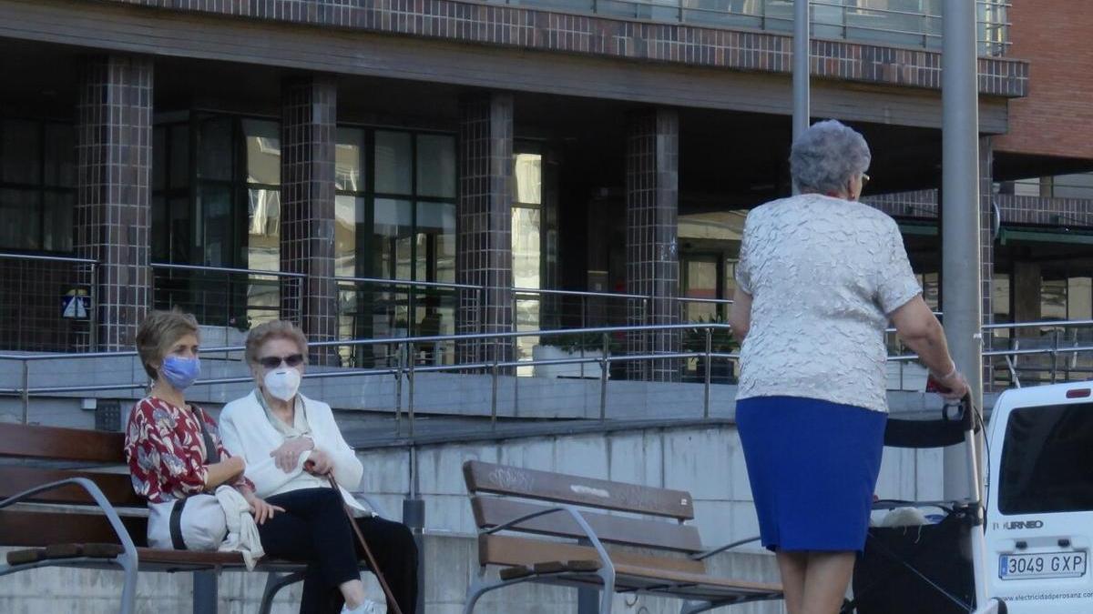 Varias ancianas pasean ante una residencia.