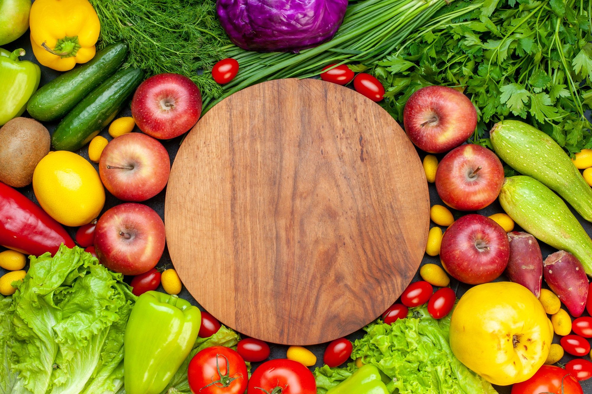 Frutas y verduras alrededor de una tabla de cortar.