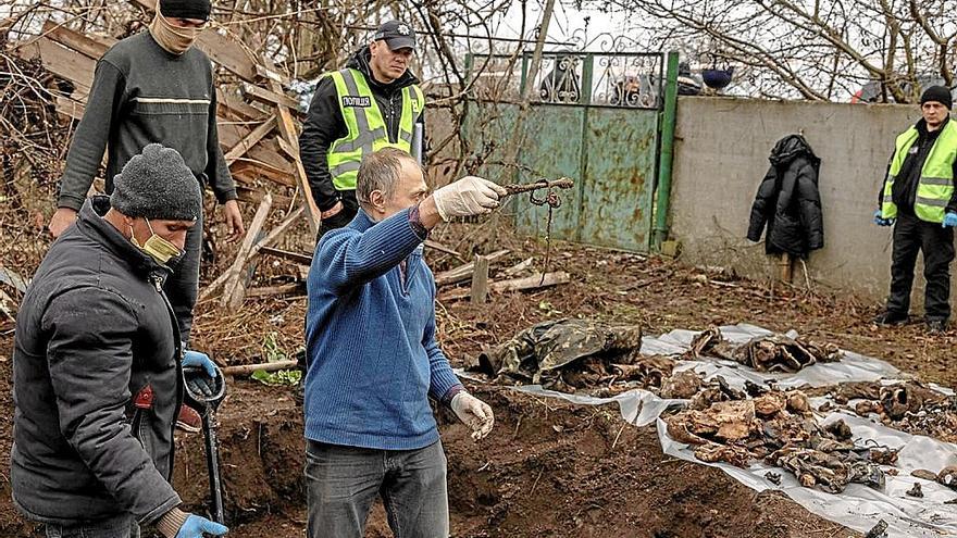 Forenses recogen cuerpos de ucranianos encontrados en fosas en Jersón tras la retirada de los rusos. | FOTO: EFE