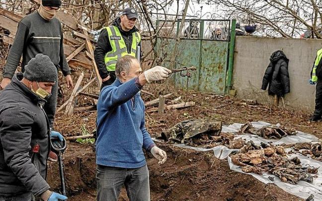 Forenses recogen cuerpos de ucranianos encontrados en fosas en Jersón tras la retirada de los rusos. | FOTO: EFE