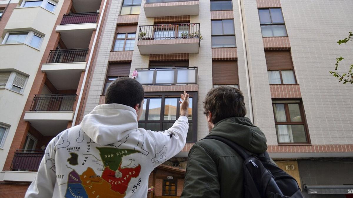 Dos jóvenes contemplan un bloque de viviendas en Bilbao