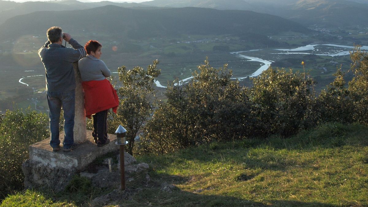 Ereñozar mendi puntan bisitari bi, azpiko Urdaibaiko padurak ikuskatzen dituztelarik.