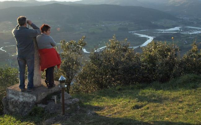Ere&ntilde;ozar mendi puntan bisitari bi, azpiko Urdaibaiko padurak ikuskatzen dituztelarik.